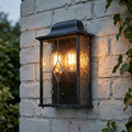 Traditional Elstead Wexford black and silver outdoor wall lantern with leaded glass on a white brick wall.