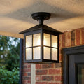 Black lantern-style outdoor ceiling light with windowpane glass panels mounted on a porch ceiling.