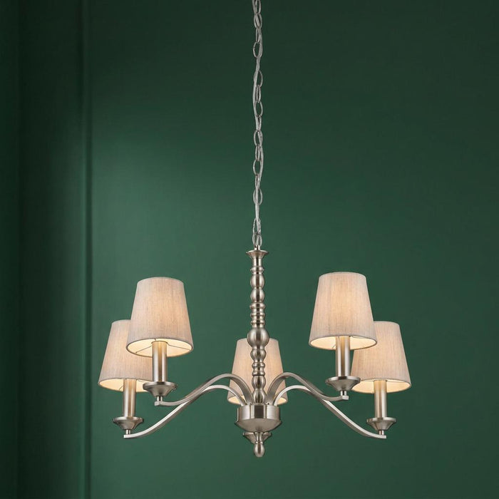 Satin nickel 5-arm chandelier with cotton shades hanging against a deep green wall.