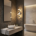 Modern spiral chrome LED wall light glowing on a dark stone wall in a luxury bathroom with a marble vanity.