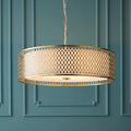 Endon Cordero 3-light gold ceiling pendant with a lattice drum shade against a teal paneled wall.