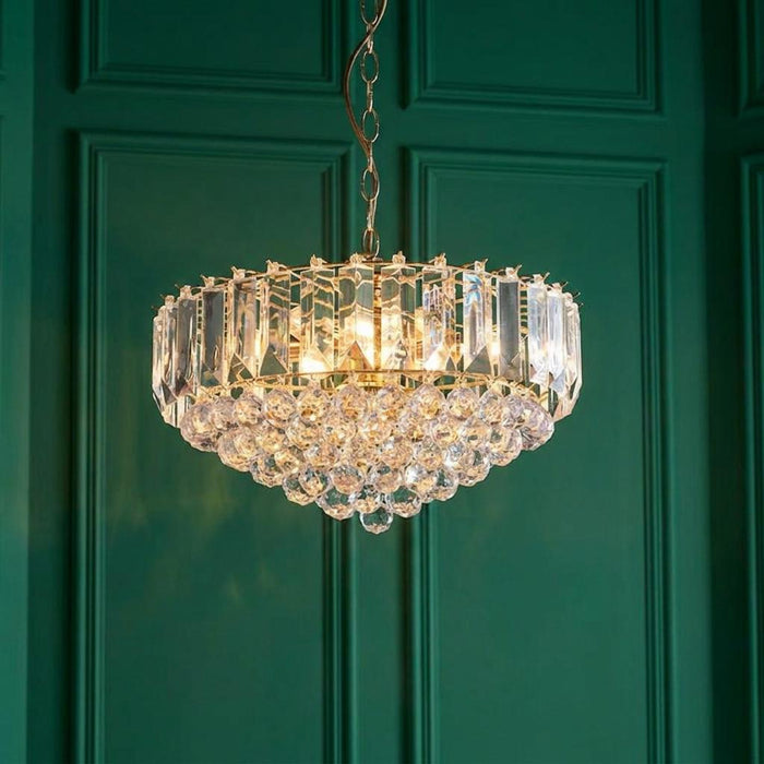 Endon Fargo 6-light pendant with clear acrylic crystals hanging against a dark green paneled wall.
