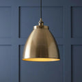 Antique brass dome-shaped pendant light against a blue paneled wall.