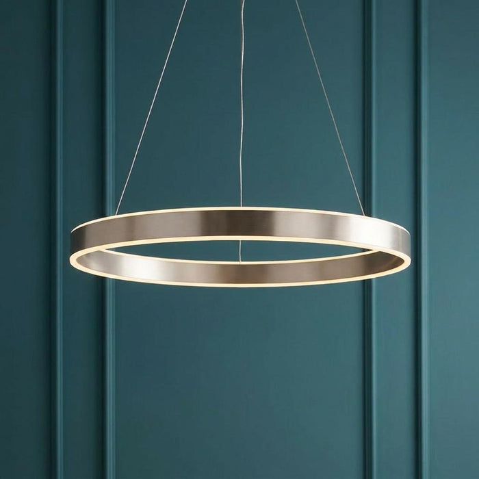 Modern circular LED pendant light in brushed nickel hanging against a dark teal paneled wall.