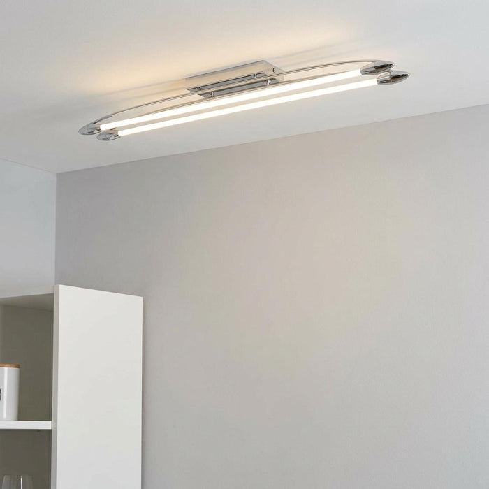 Large chrome-finished LED flush ceiling light with two parallel illuminated tubes in a minimalist modern setting.