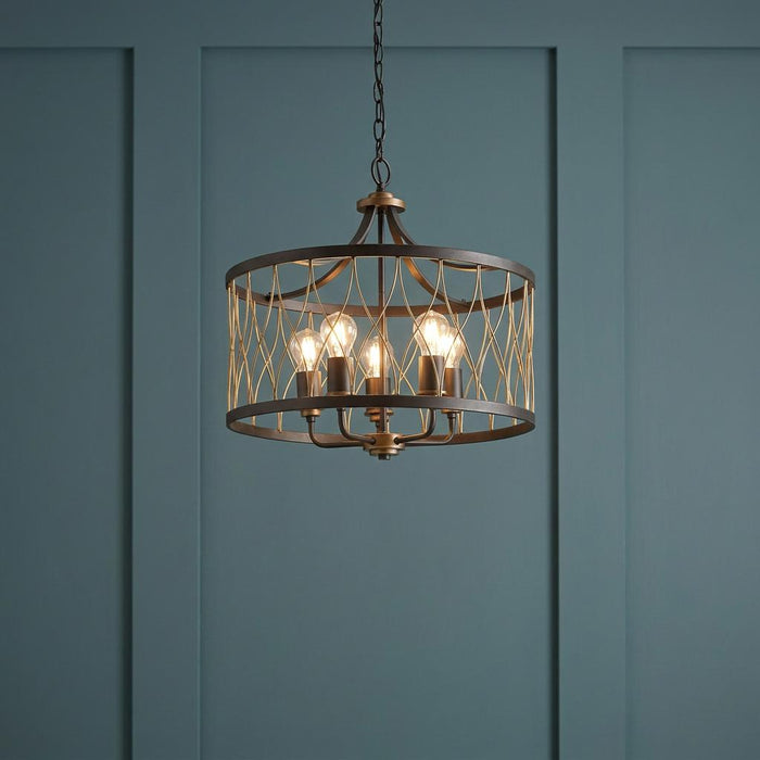 Five-light black and bronze drum pendant with wire lattice detail against a teal blue panelled wall.