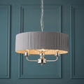 3-light pendant featuring a charcoal pleated shade and bright nickel finish set against a teal paneled wall.