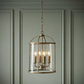 Four-light brass ceiling lantern with a clear glass cylinder hanging against a pale green paneled wall.