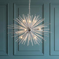 Starburst-style chrome chandelier with glass spikes and nine lights, hanging against a teal paneled wall.