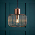 Antique copper wire cage pendant light with a glowing bulb against a teal paneled wall.