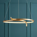 Modern gold curved ring LED pendant light suspended against a teal wainscoted wall.