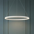 A modern matt white halo-style LED pendant light suspended against a grey-green panelled wall.