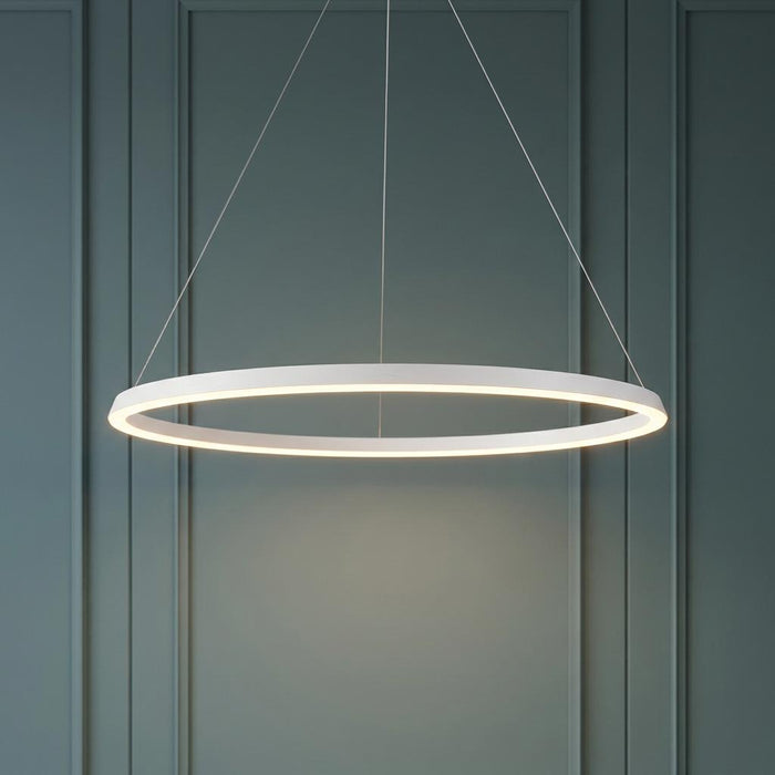 A modern matt white halo-style LED pendant light suspended against a grey-green panelled wall.