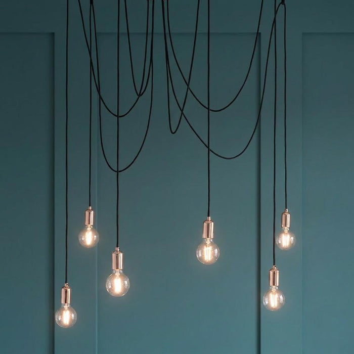 Endon Studio 6 light copper ceiling pendant with exposed Edison bulbs against a teal panelled wall.