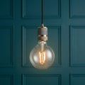 Endon Urban 1 Light Brass Ceiling Pendant with a large filament globe bulb against a teal paneled wall.