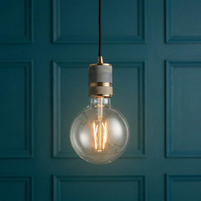 Endon Urban 1 Light Brass Ceiling Pendant with a large filament globe bulb against a teal paneled wall.