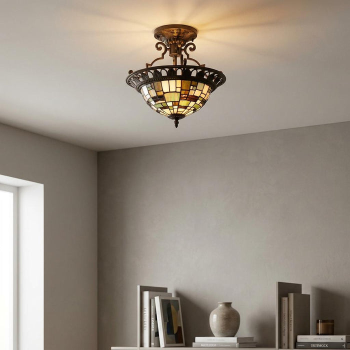 Geometric stained glass semi-flush Tiffany ceiling light with a bronze frame mounted above a bookshelf.
