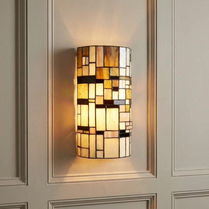 Geometric Tiffany wall light with amber and cream glass panels mounted on a light paneled wall.
