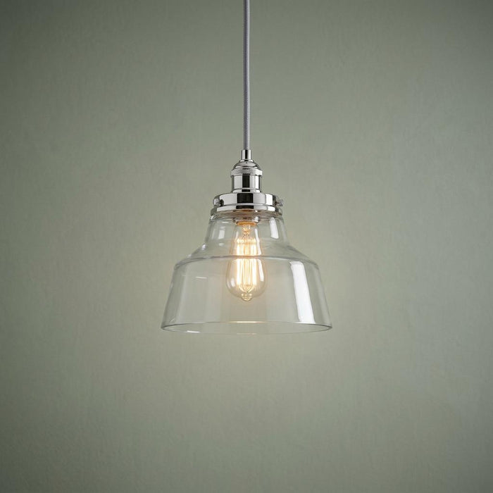 Feiss Baskin polished nickel ceiling pendant with clear glass bell shade and vintage bulb against a green wall.