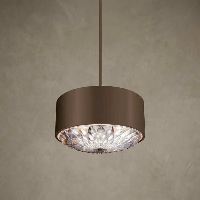 Aged brass drum pendant light featuring an intricate, glowing petal-patterned glass diffuser.