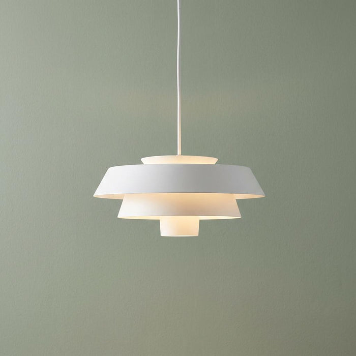 Feiss Brisbin 1 light matte white tiered pendant ceiling light illuminated against a sage green wall.