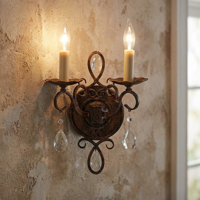 Feiss Chateau two-light bronze wall sconce with teardrop crystals mounted on a rustic plaster wall.