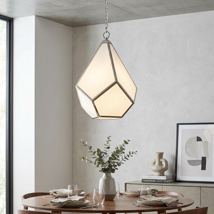 Geometric diamond-shaped pendant chandelier in polished nickel hanging over a modern wooden dining table.