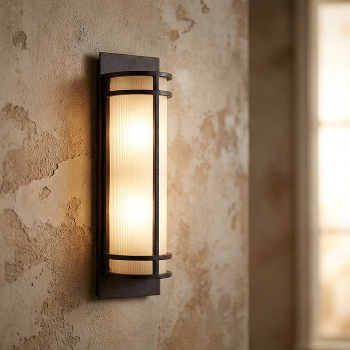 Feiss Fusion 2 Light Grecian Bronze wall light with vertical textured glass on a rustic stone wall.
