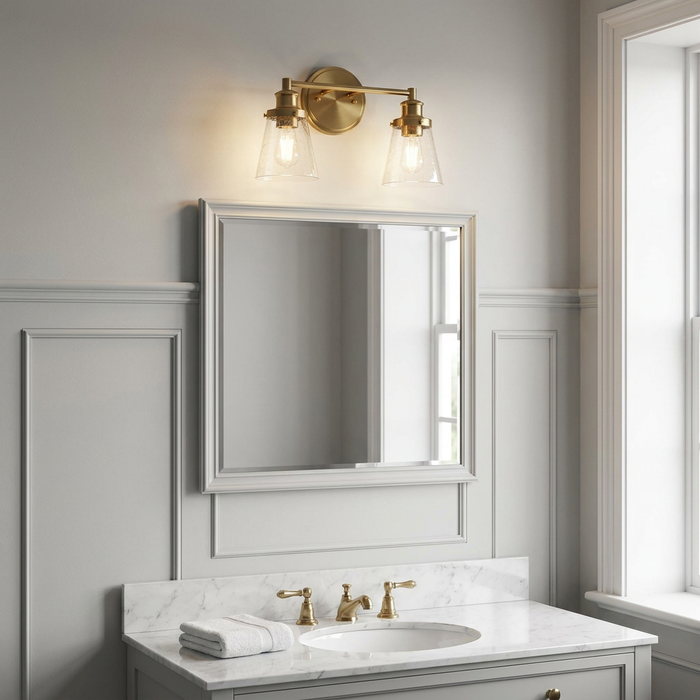 Feiss Huguenot Lake two-light brass vanity fixture with seeded glass shades mounted above a bathroom mirror.