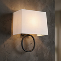 Feiss Indo wall light with a white rectangular fabric shade and an aged iron ring on a textured wall.