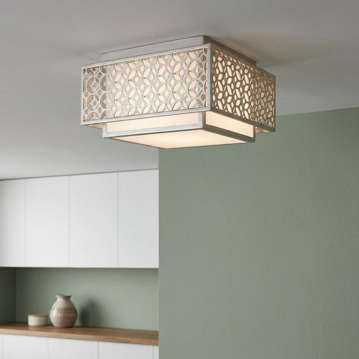 Square flush mount ceiling light with a silver geometric lattice frame and white diffuser against a green wall.