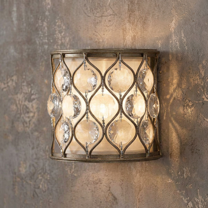 Silver lattice wall sconce featuring hanging crystals and a cream shade mounted on a textured wall.