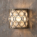 Silver lattice wall sconce featuring hanging crystals and a cream shade mounted on a textured wall.