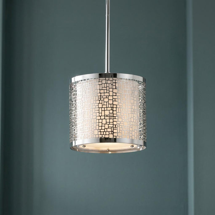 Chrome drum pendant light with a geometric cutout pattern and white inner shade, suspended from a rod.