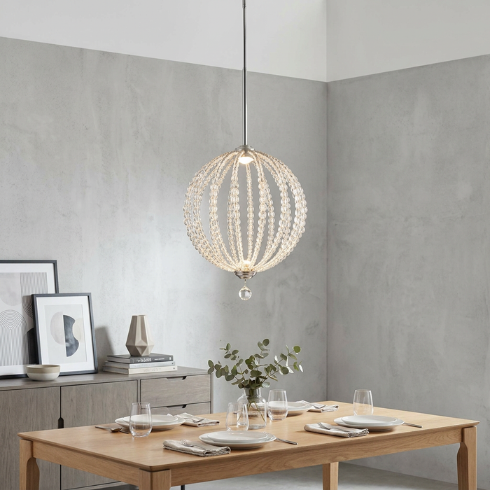 Feiss Oberlin beaded globe LED pendant light hanging over a set wooden dining table in a modern room.