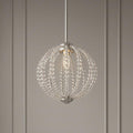 A satin nickel LED pendant light featuring a spherical cage of clear glass beads against a neutral paneled wall.