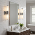 Two chrome twin-arm wall lights with opal glass cylinders flanking a bathroom mirror on white subway tiles.