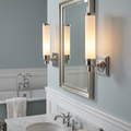 Two Feiss Payne polished chrome wall lights with cylindrical white shades flanking a bathroom mirror.