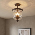 Feiss Pickering bronze semi-flush ceiling light with a bell-shaped seeded glass shade and three glowing bulbs.