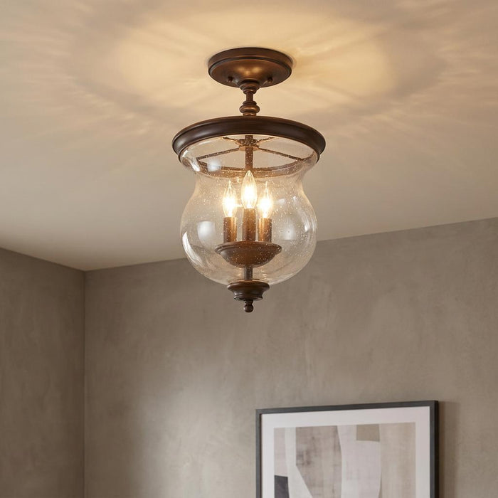 Feiss Pickering bronze semi-flush ceiling light with a bell-shaped seeded glass shade and three glowing bulbs.