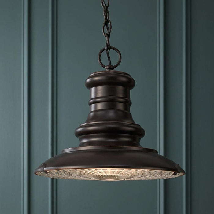 Feiss Redding Station bronze outdoor pendant light with textured glass diffuser against a dark paneled wall.
