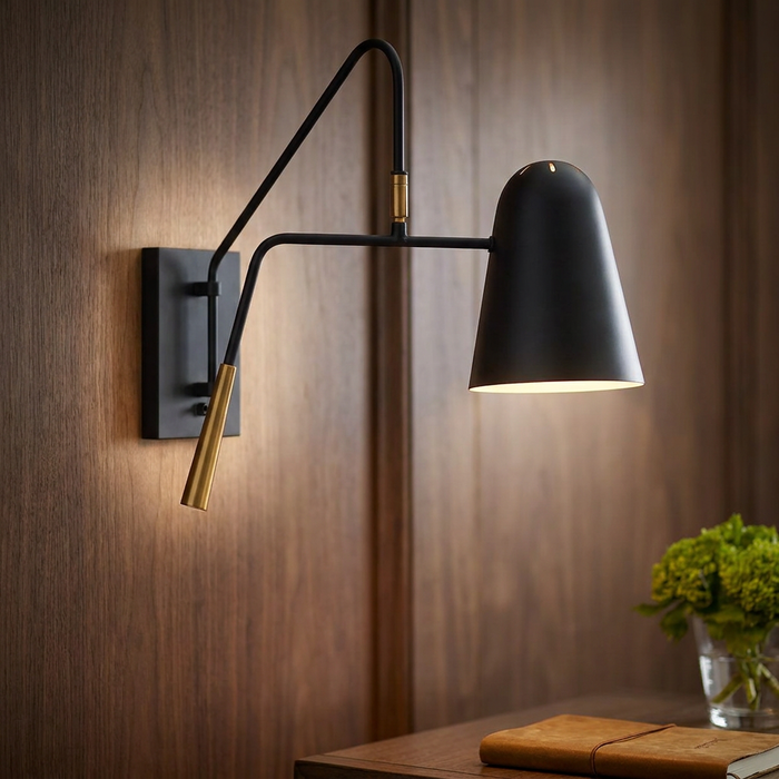 A Feiss Simon black wall light with a brass finish swing arm against a wood panelled wall.