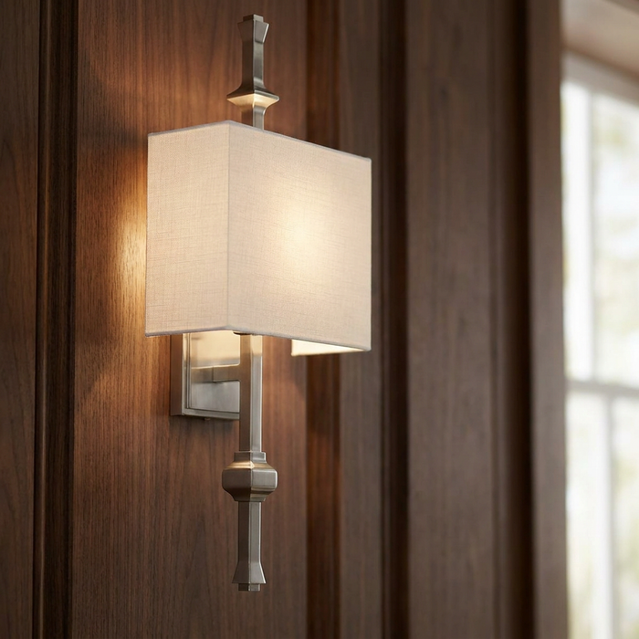 Polished nickel wall sconce with a rectangular fabric shade mounted on dark wood paneled walls.