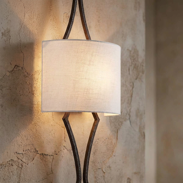 Feiss Tilling wall light with a weathered iron frame and cream linen shade on a rustic textured wall.