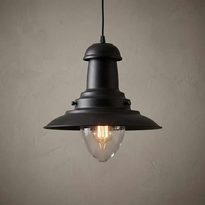 Fisherman-style black pendant light with a clear glass dome and glowing Edison bulb against a beige wall.