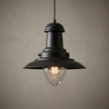 Fisherman-style black pendant light with a clear glass dome and glowing Edison bulb against a beige wall.