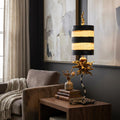 Flambeau Dominique table lamp with a striped shade and gold coral accents on a wooden side table in a modern room.
