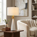 White conical table lamp with a gold coral accent and drum shade on a wooden side table in a lounge.
