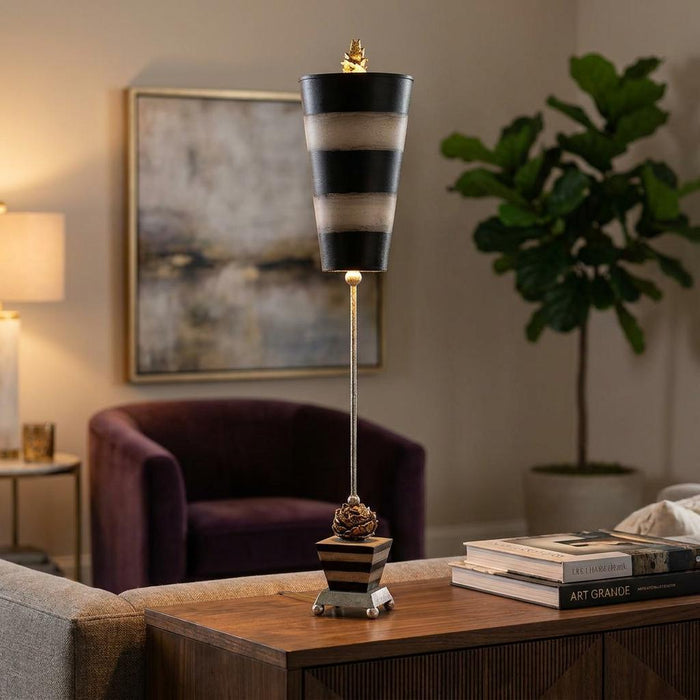 Slim table lamp with a taupe and black striped conical shade and peony detail, set on a wooden living room table.