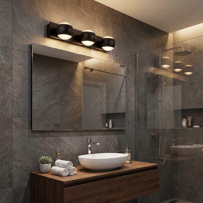 Flare 3 Light black ball wall light glowing above a mirror in a contemporary tiled bathroom.